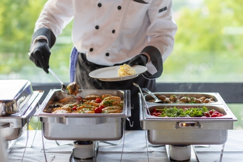 Chef,serving,a,delicious,buffet,meal,featuring,grilled,chicken,,fresh